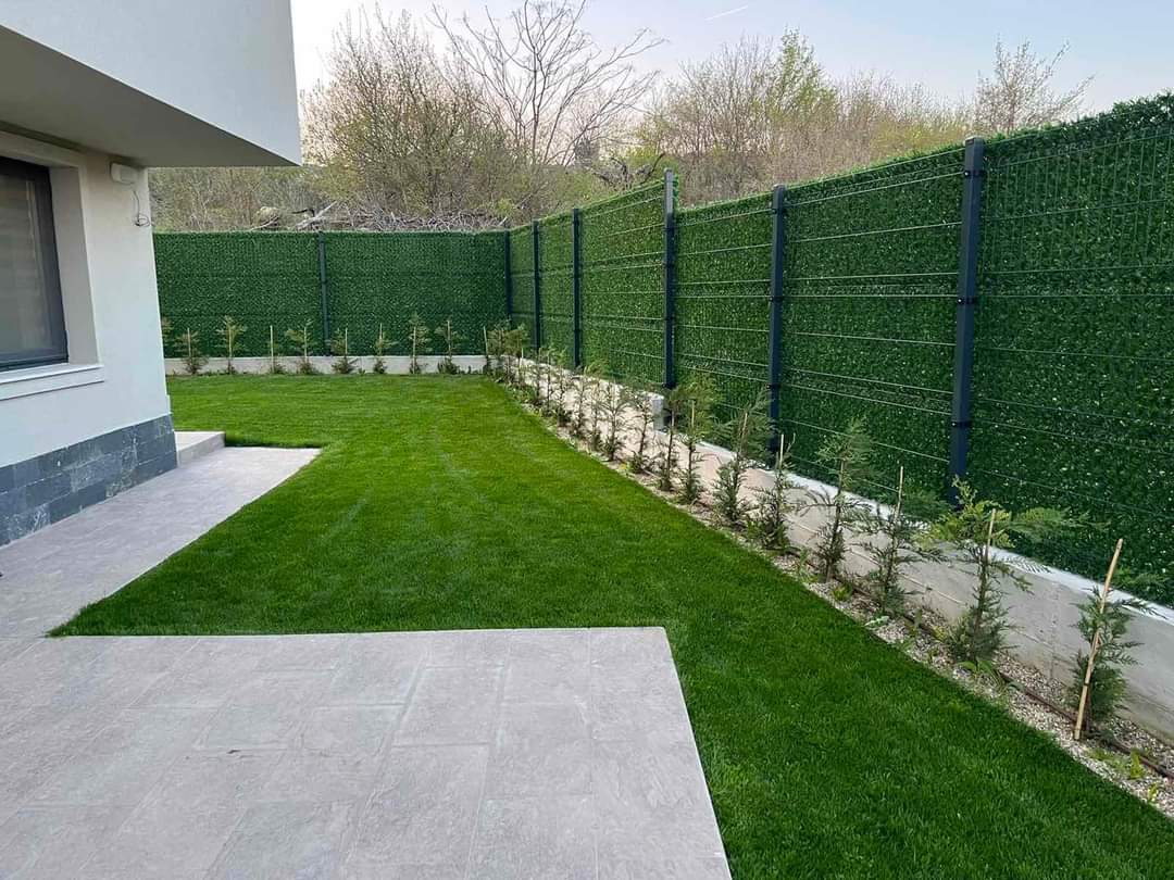 ограда направена от оградни пана и колове атнрацит сиви и декоративна мрежа жив плет